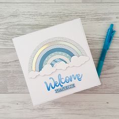 a welcome little one card with a blue pen next to it on a wooden surface