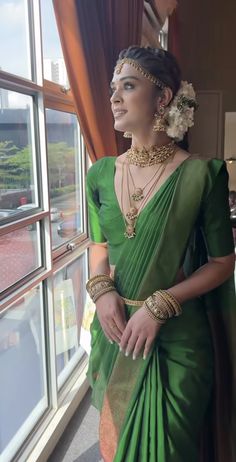 a woman in a green sari standing next to a window