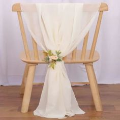 a wooden chair with a white cloth draped over it and flowers on the seat back