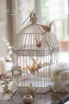 a bird in a cage with flowers on the table