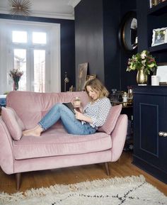 a woman is sitting on a pink couch