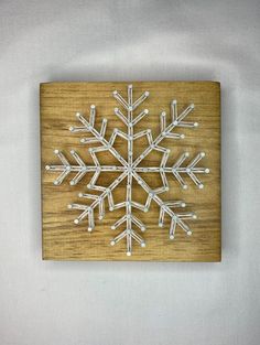 a wooden snowflake is mounted on a white wall and it looks like an ornament