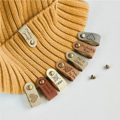 several different types of luggage tags on a white surface next to a yellow sweater and screws