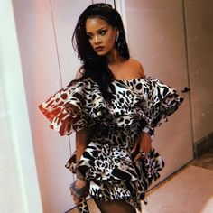 a woman standing in front of a mirror wearing a dress with leopard print on it