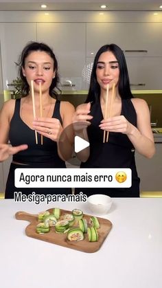 two women standing in front of a white counter top with food on sticks next to them