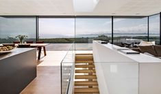 an open concept living room and dining area with glass walls overlooking the ocean in this modern home