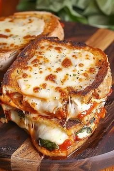 a grilled cheese sandwich with tomato sauce and basil on a cutting board next to some bread