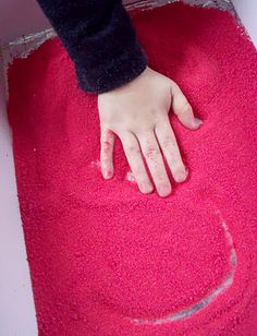 a child's hand on a red rug