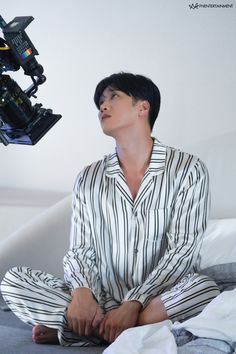 a man sitting on top of a bed next to a camera