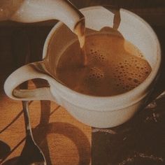 a pitcher filled with liquid sitting on top of a table next to spoons and utensils