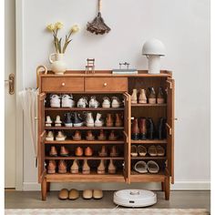 a wooden cabinet filled with lots of shoes next to a wall mounted clock and lamp