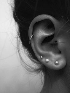 a woman's ear with three piercings on it