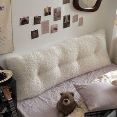 a teddy bear sitting on top of a bed in a room with pictures on the wall