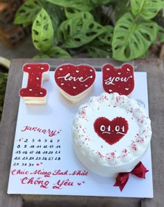 a cake and two cookies are on a card with the word i love you written on it