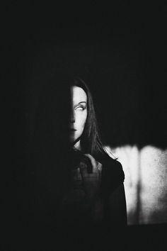 a black and white photo of a woman's face with long hair in the dark