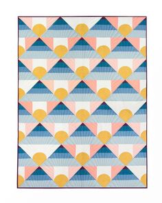 a colorful quilt with geometric shapes on the front and back, in blue, pink, yellow