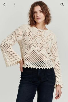 a woman is wearing a sweater with crochet on the sleeves and bottom, standing in front of a white background