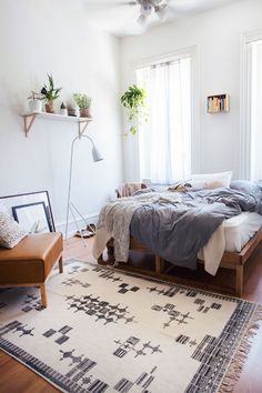 a bed sitting on top of a wooden floor next to a chair and table in a bedroom