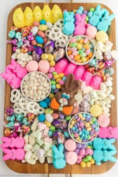 a wooden tray filled with lots of colorful candies and chocolate bunny ears on top of it