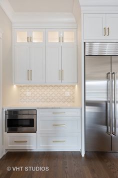 a kitchen with white cabinets and stainless steel refrigerator freezer combo in the center, along with hardwood flooring