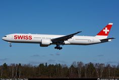 an airplane is flying in the sky over some trees and grass with its landing gear down