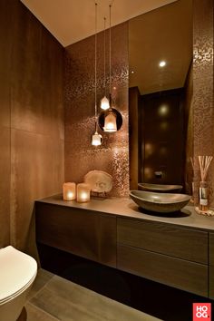 a modern bathroom with candles and lights on the counter top, along with a large bowl shaped vessel sink