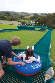 two children are playing on an inflatable float at the park while adults watch