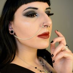 a woman with black hair and piercings on her nose