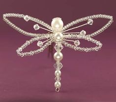 a white dragon brooch with pearls on it's wings and beads attached to the back