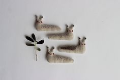 three small stuffed animals sitting on top of a white surface next to an olive branch