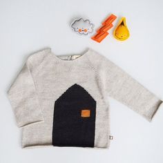 a sweater with a house on it next to toys