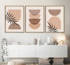 three abstract paintings on the wall above a white cabinet