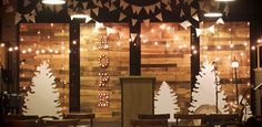 a room filled with lots of wooden tables and chairs next to tall windows covered in lights