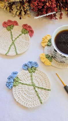 crocheted coasters with flowers on them next to a cup of coffee