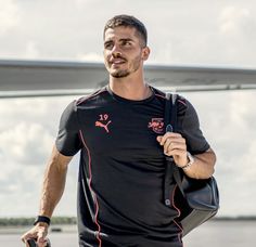 a man holding a tennis racquet on top of a tennis court next to an airplane