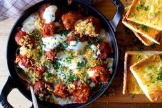 a skillet filled with meatballs, cheese and bread