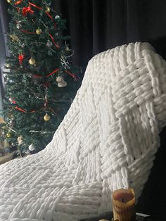 a white blanket sitting on top of a table next to a christmas tree