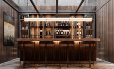 a bar with stools and bottles on the shelves in a room that has wood paneling