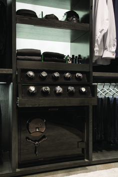 an oven in a closet with clothes hanging on the wall and shelves above it that are open