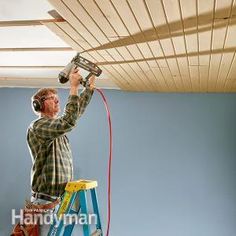 a man is painting the ceiling in his room with headphones and a paint roller