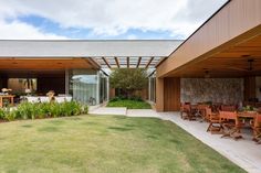 an outdoor dining area with wooden tables and chairs next to a stone wall that extends into the back yard