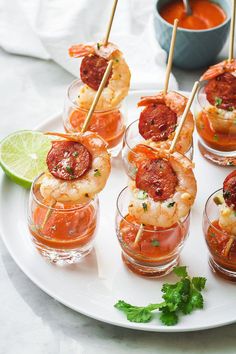 small glasses filled with shrimp and garnished with toothpicks on a white plate