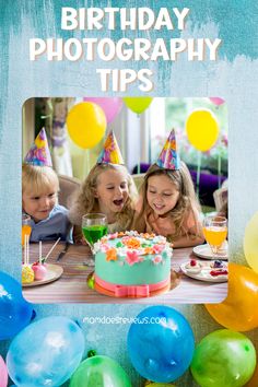 three children are sitting at a table with a birthday cake and balloons in front of them