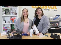 two women standing next to each other in front of a table with supplies on it