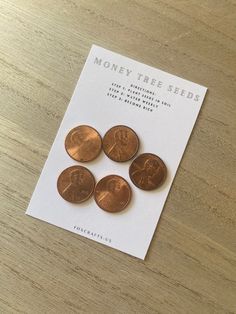 four pennys sitting on top of a wooden table next to a white piece of paper