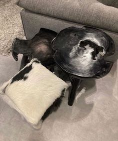 a black and white table sitting on top of a floor next to a gray couch