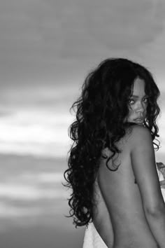 black and white photograph of a woman in towel on the beach with her back to the camera