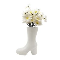 a white vase filled with flowers on top of a white flooring next to a pair of boots