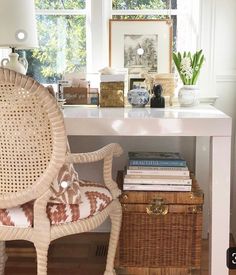 a wicker chair sitting in front of a white desk with a lamp on it