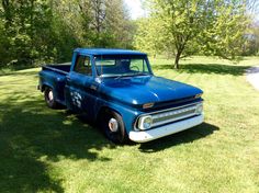 an old blue truck parked in the grass